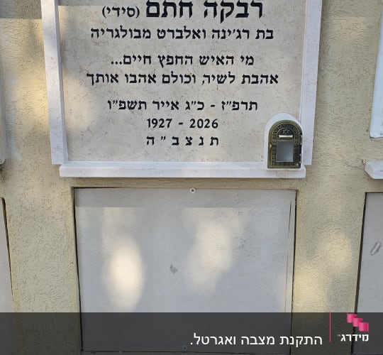 מצבה עם כיתוב בעברית על קיר חיצוני